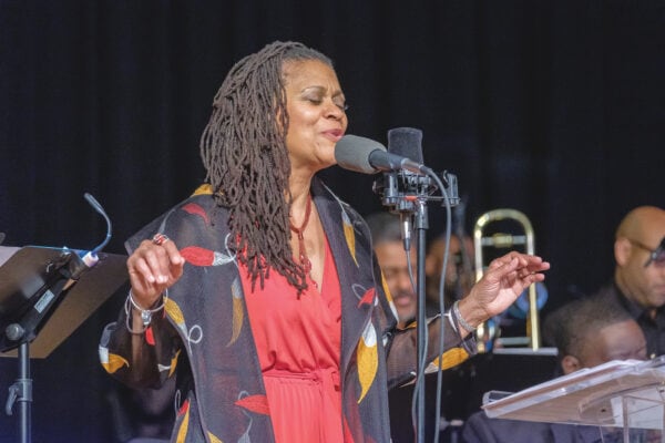 Lenora Helm Hammonds singing into microphone with jazz ensemble behind her