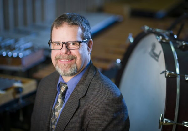 headshot of Christopher Johnson with band instruments in the background