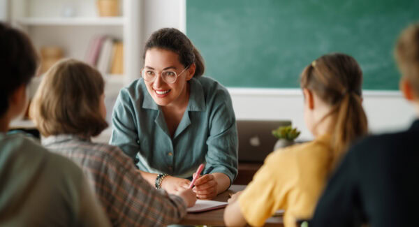 smiling teacher in classroom discussion with students